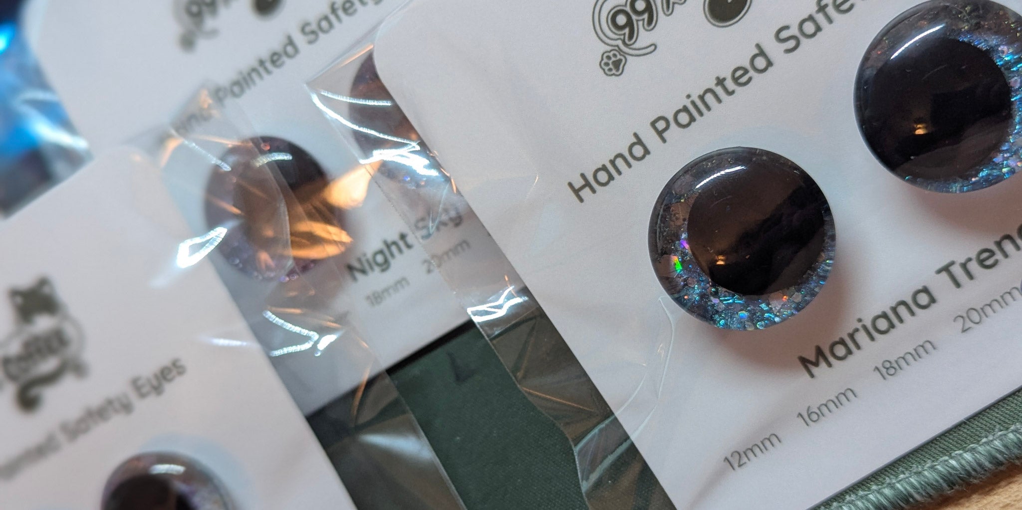 Pair of hand-painted safety eyes with packaging on a white background